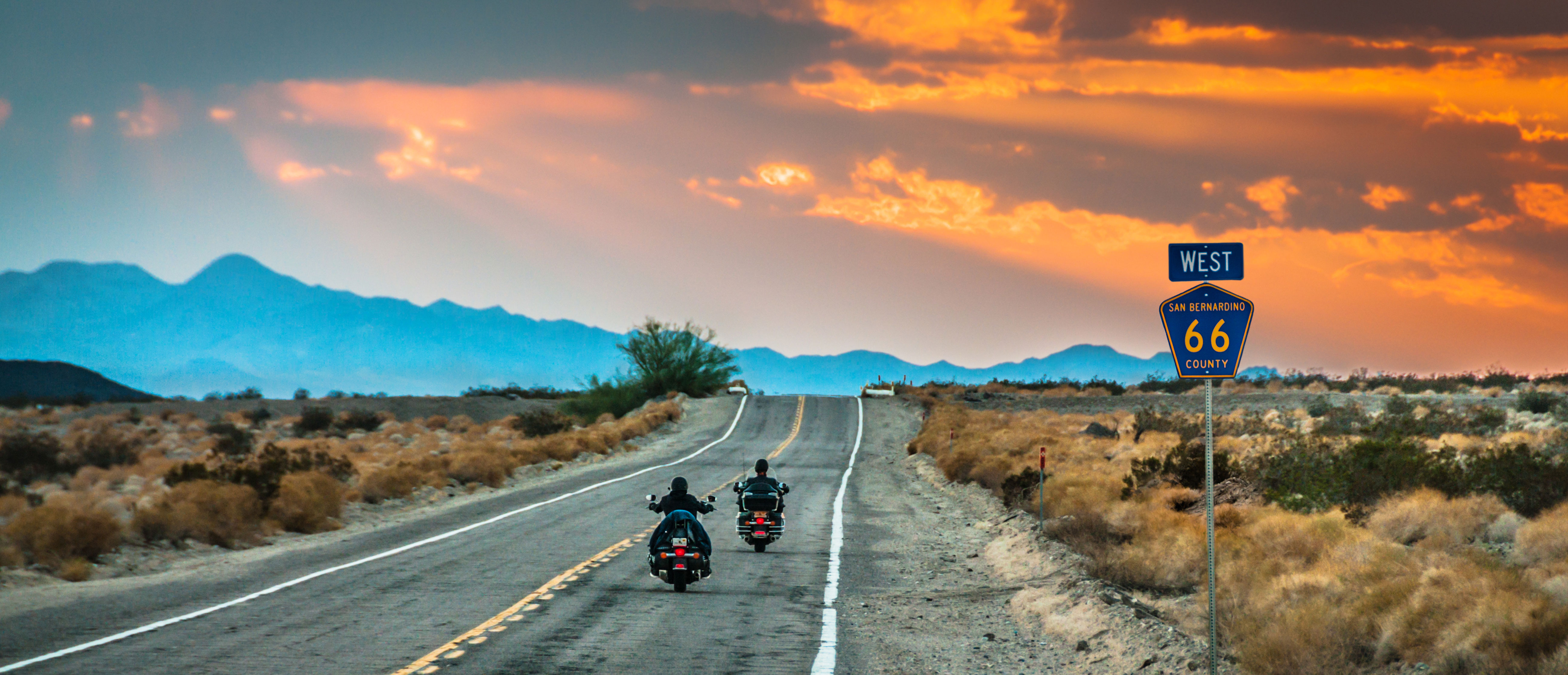 Motorcycles cruising through the California desert on Route 66 at sunset