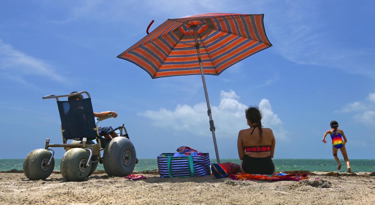 坐在沙滩轮椅上，在佛罗里达州比斯坎湾的无障碍海滩上享受阳光与海